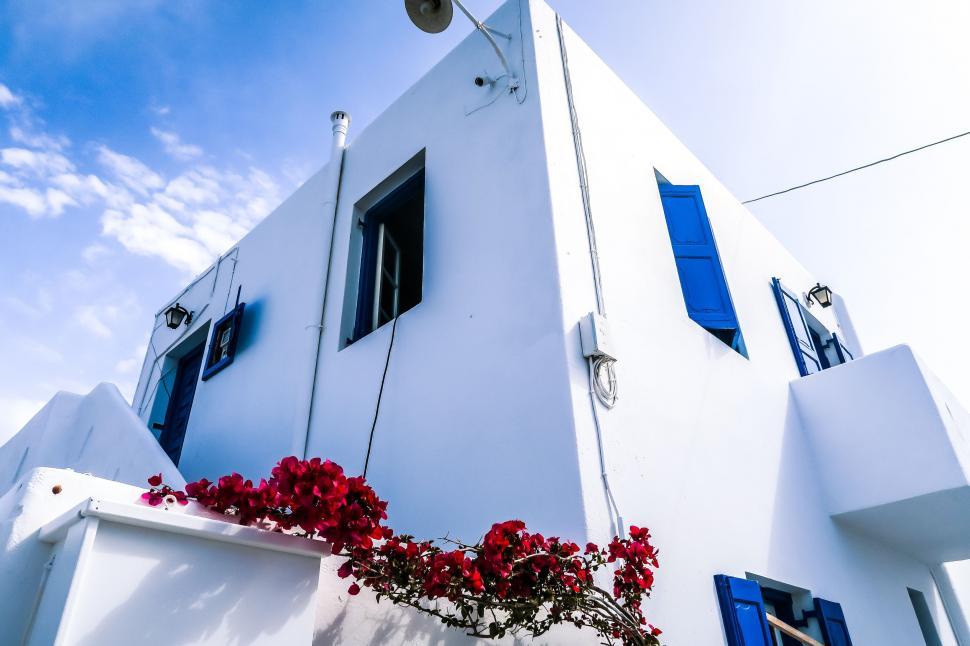 Free Image of White Building With Blue Shutters and Red Flowers 