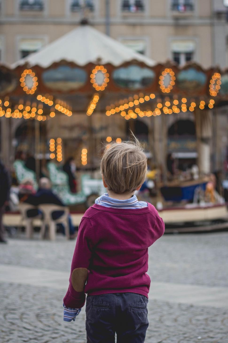 Free Image of Little Boy Standing in Front of Merry Go Round 