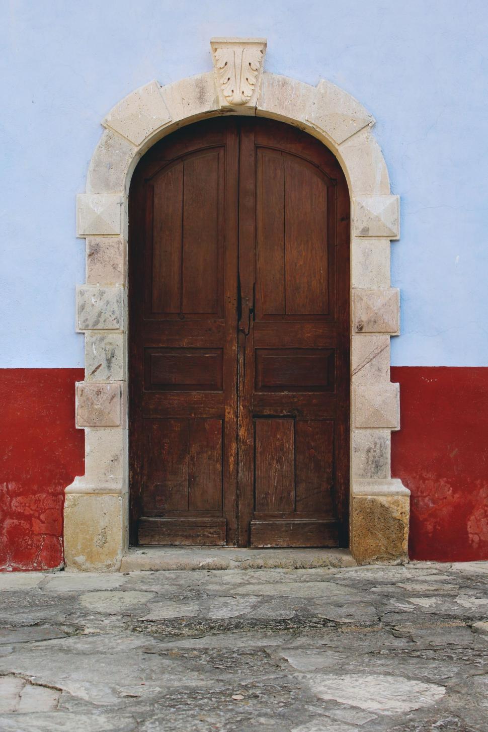 Free Image of Large Wooden Door Against Blue and Red Wall 