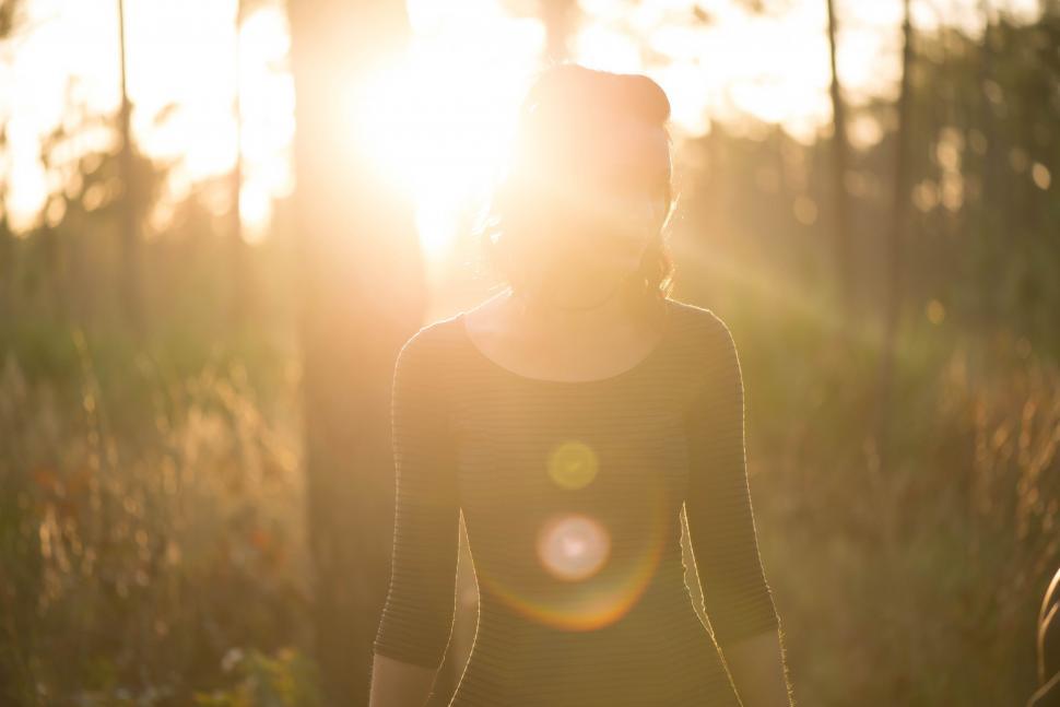 Free Image of Woman Walking Through Forest at Sunset 