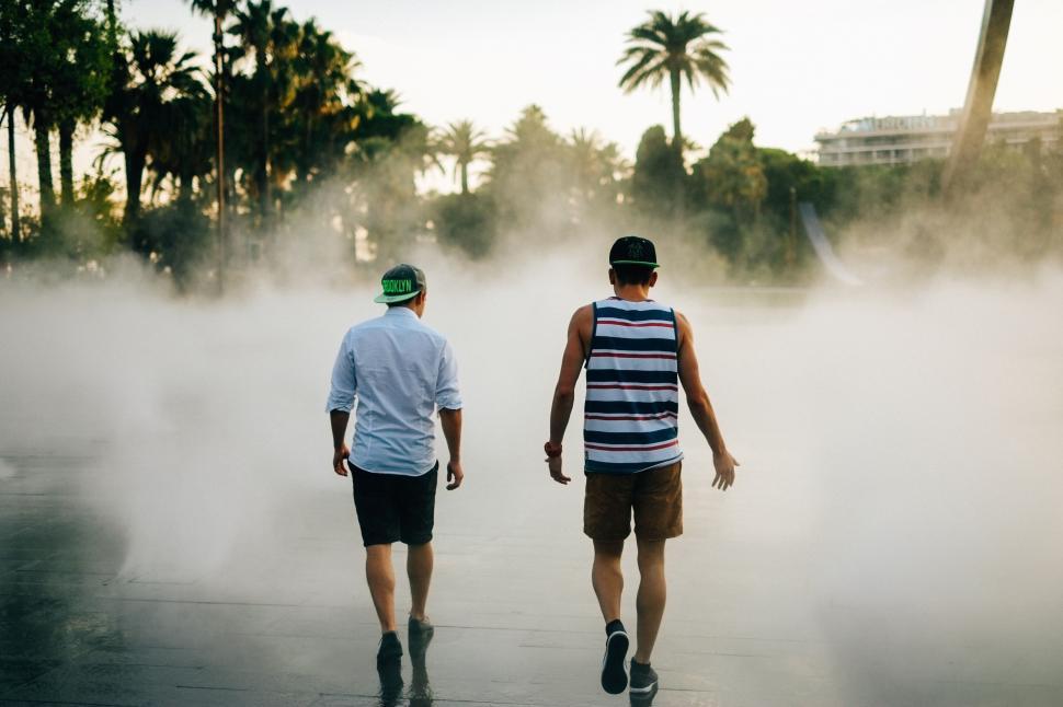 Free Image of Men Walking Down Street Near Cloud of Smoke 