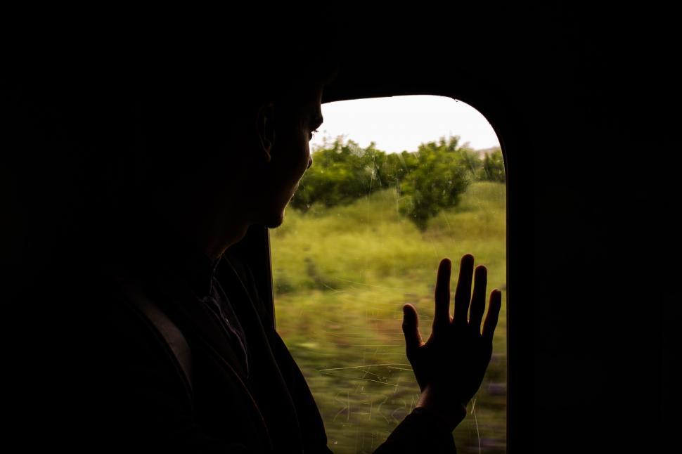 Free Image of Silhouette of Person Holding Hands Out of Window 