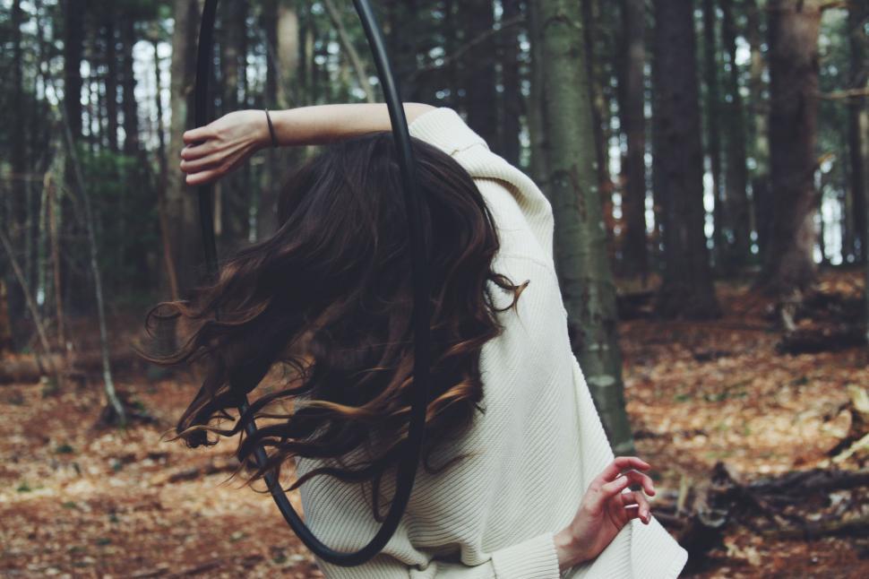 Free Image of Woman Standing in Forest With Windblown Hair 