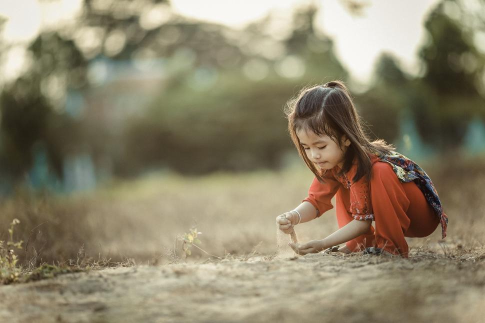 Free Image of Little Girl in Red Shirt Playing in Grass 