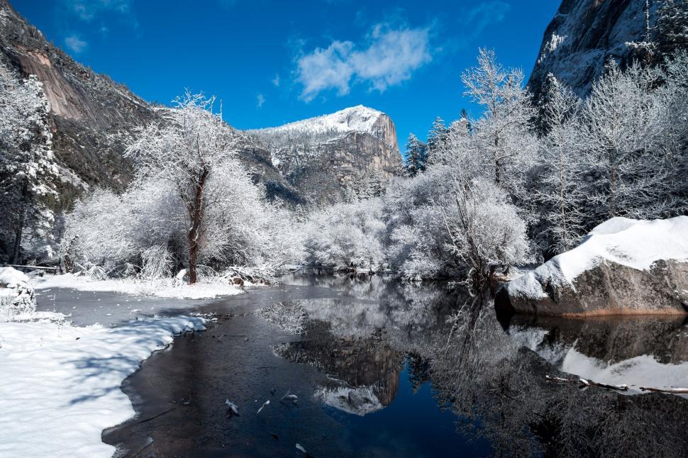 Free Image of Snow-Covered Mountains Surrounding River Under Blue Sky 