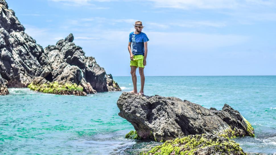 Free Image of Man Standing on Rock by Ocean 