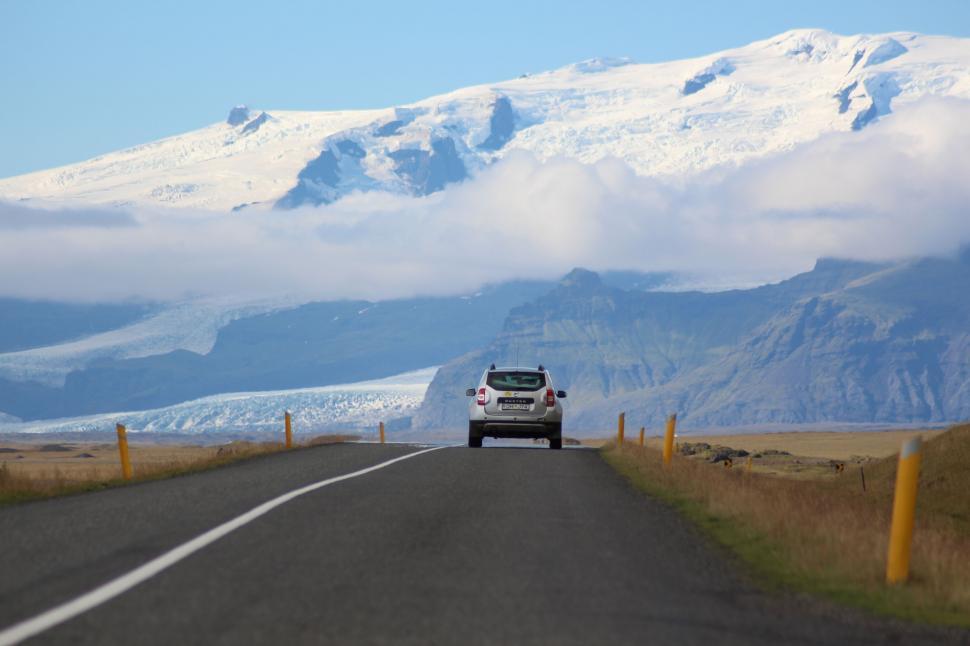 Free Image of Car Driving Down Road With Background Mountain 
