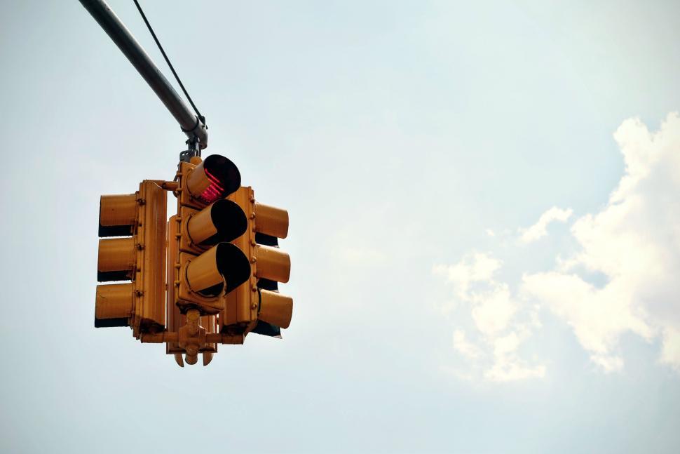 Free Image of Traffic Light Hanging From Wire With Sky Background 