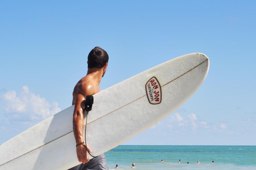 Free Image of Man Carrying a Surfboard on Beach 