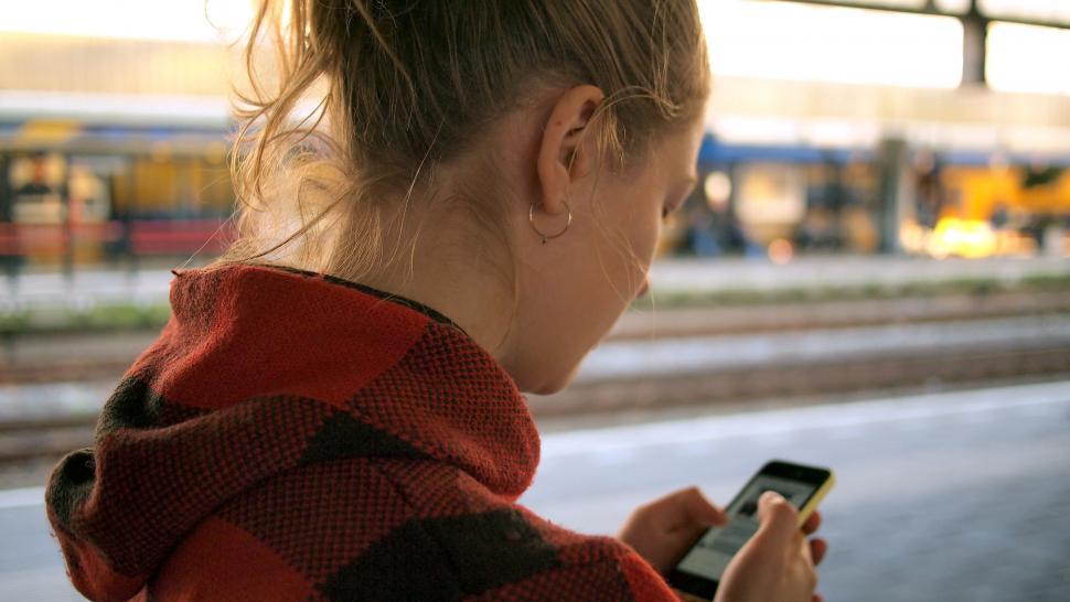 Free Image of Woman Checking Cell Phone at Train Station 