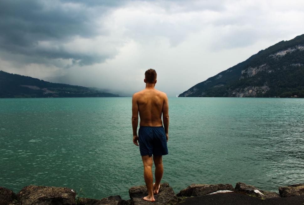 Free Image of Man Standing on Rock Overlooking Water 