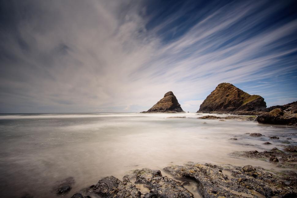 Free Image of Coastal Beach With Rocks and Water Under a Cloudy Sky 