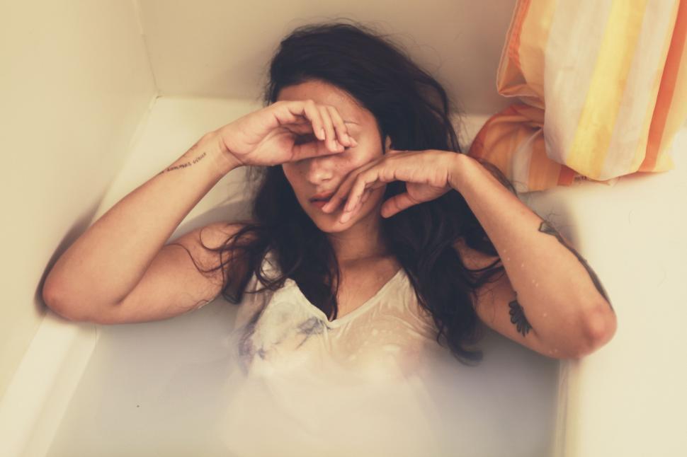 Free Image of Woman Laying in Bathtub With Hands on Face 