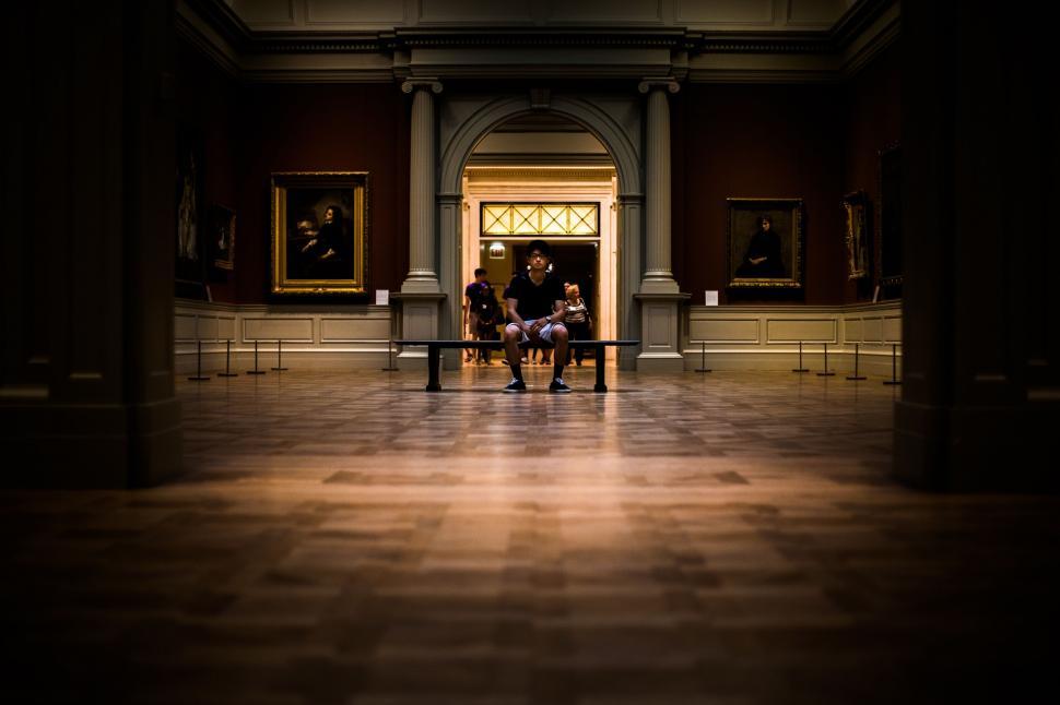Free Image of Two People Sitting on a Bench in a Dark Room 