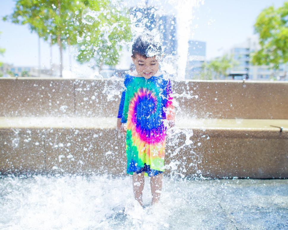 Free Image of Young Boy Standing in Fountain of Water 