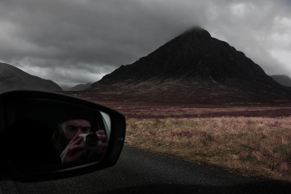 Free Image of Person Taking Picture of Mountain in Rear View Mirror 