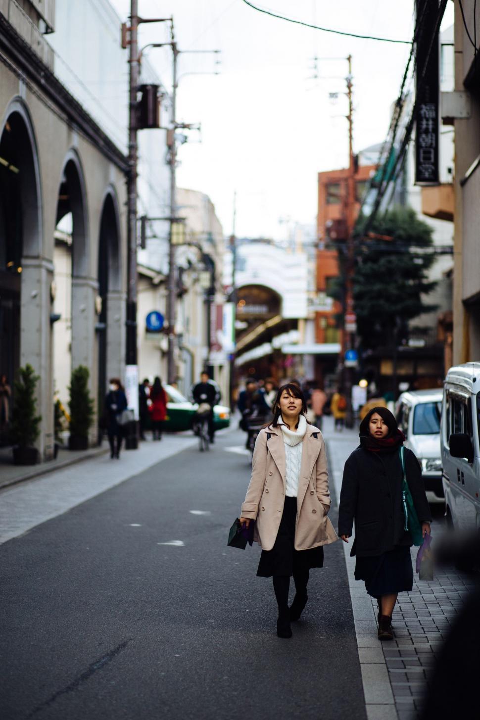 Free Image of Two Women Walking Down a City Street 