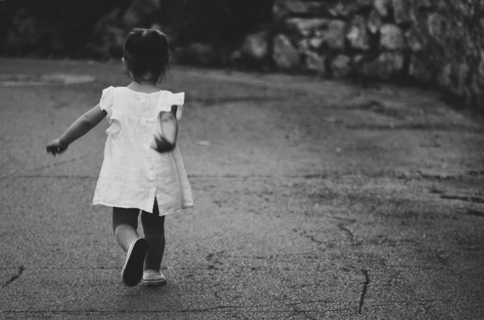 Free Image of Little Girl in White Dress Walking Down Street 