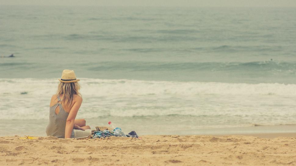 Free Image of Woman Sitting on Sandy Beach by Ocean 