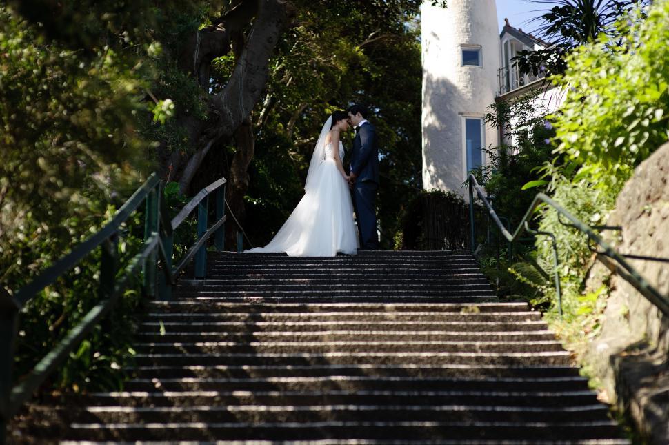 Free Image of Bride and Groom Standing on the Steps of a Lighthouse 