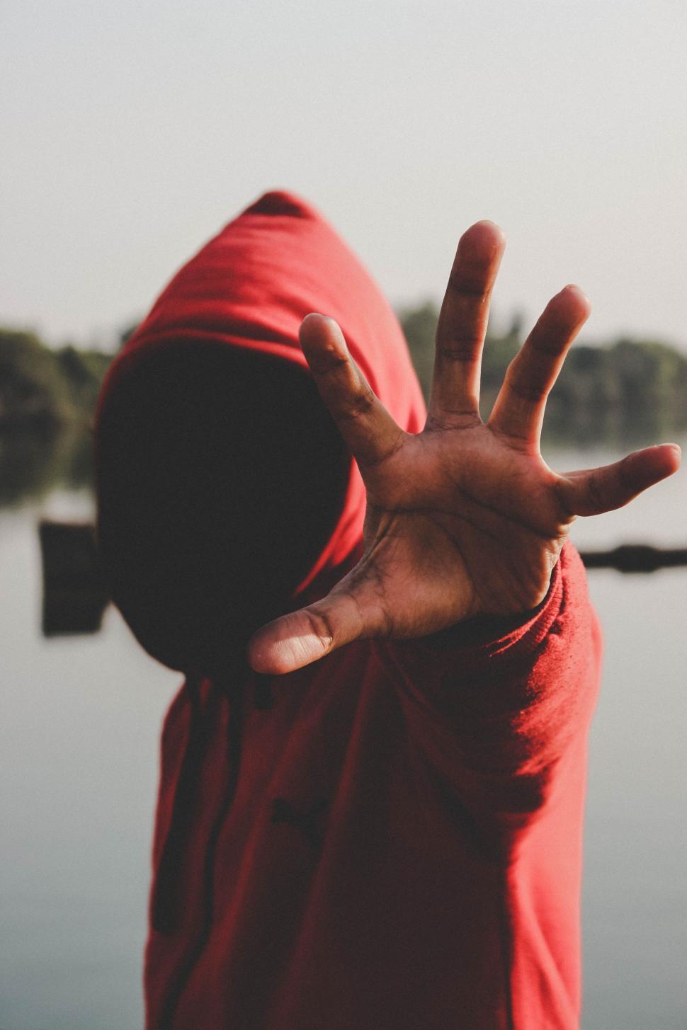 Free Image of Person in Red Hoodie Making Hand Gesture 