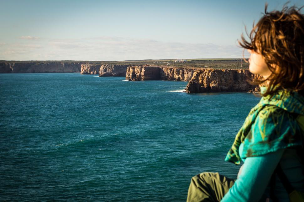 Free Image of Woman Sitting on Cliff Overlooking Ocean 