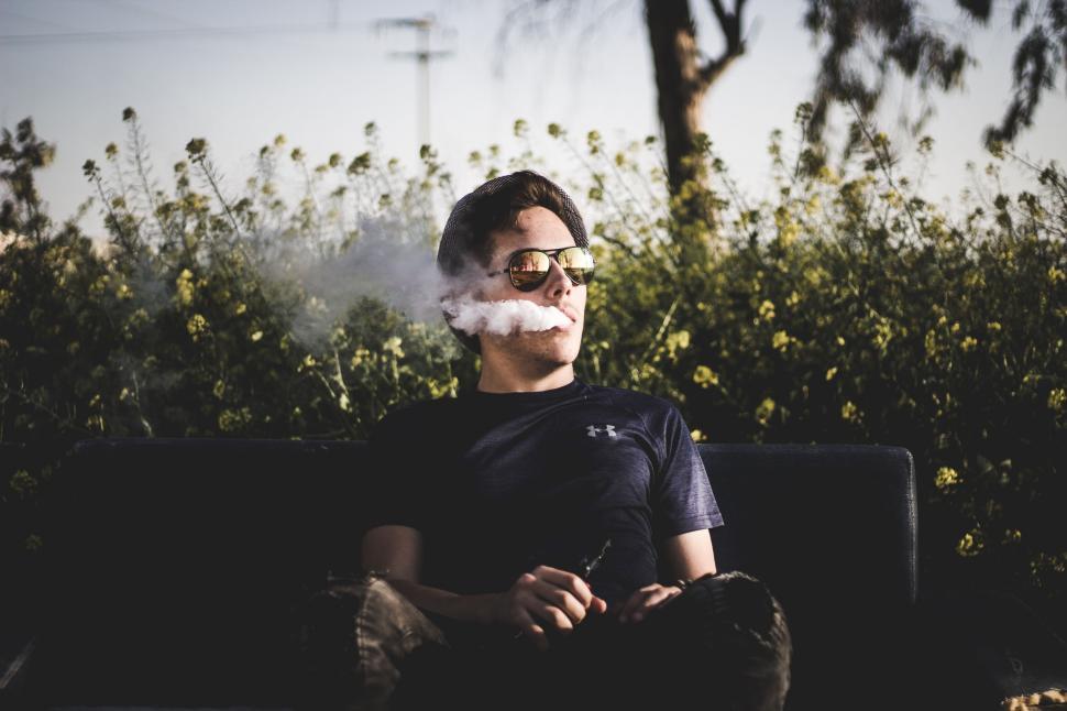 Free Image of Man Sitting on Couch Smoking a Cigarette 