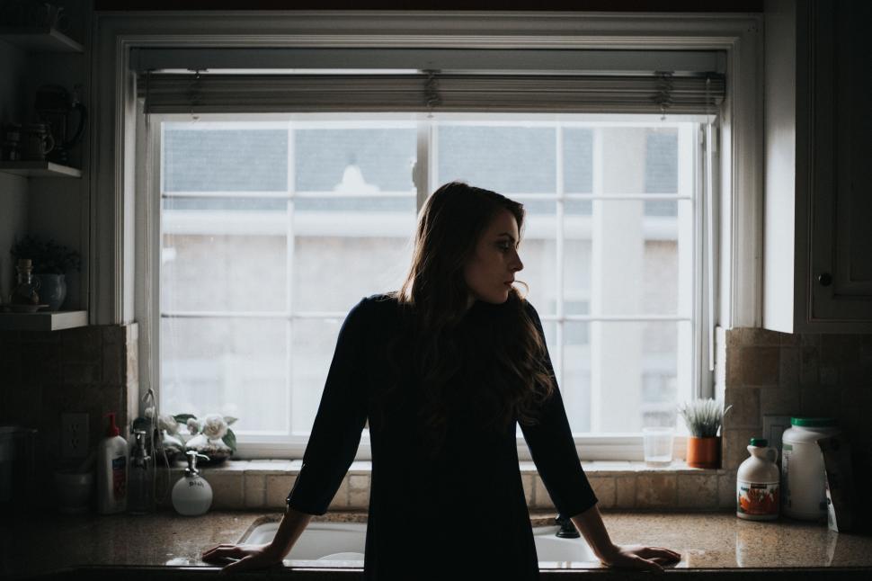 Free Image of Woman Standing in Front of Window in Kitchen 