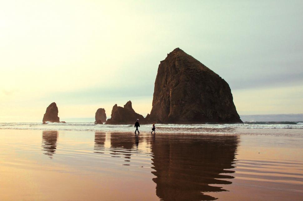 Free Image of Person Standing on Beach Next to Large Rock 
