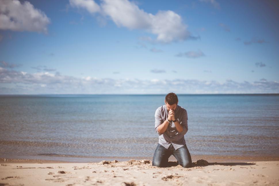 Free Image of Man Sitting on Beach With Camera 