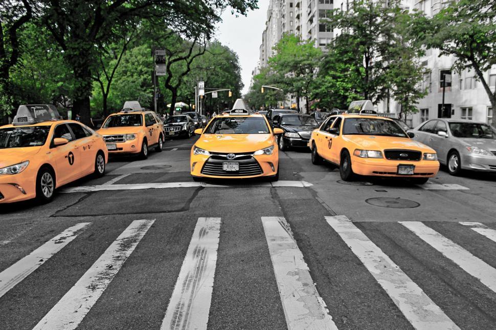 Free Image of A Group of Taxi Cabs Driving Down a Street 