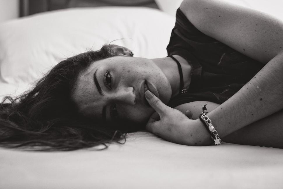 Free Image of Woman Laying on Bed in Black and White 