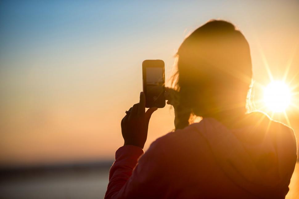 Free Image of Woman Taking Picture of the Sun With Cell Phone 