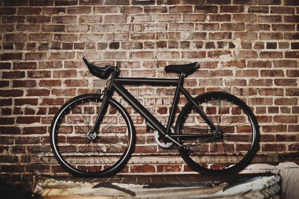 Free Image of Black Bicycle Leaning Against Brick Wall 