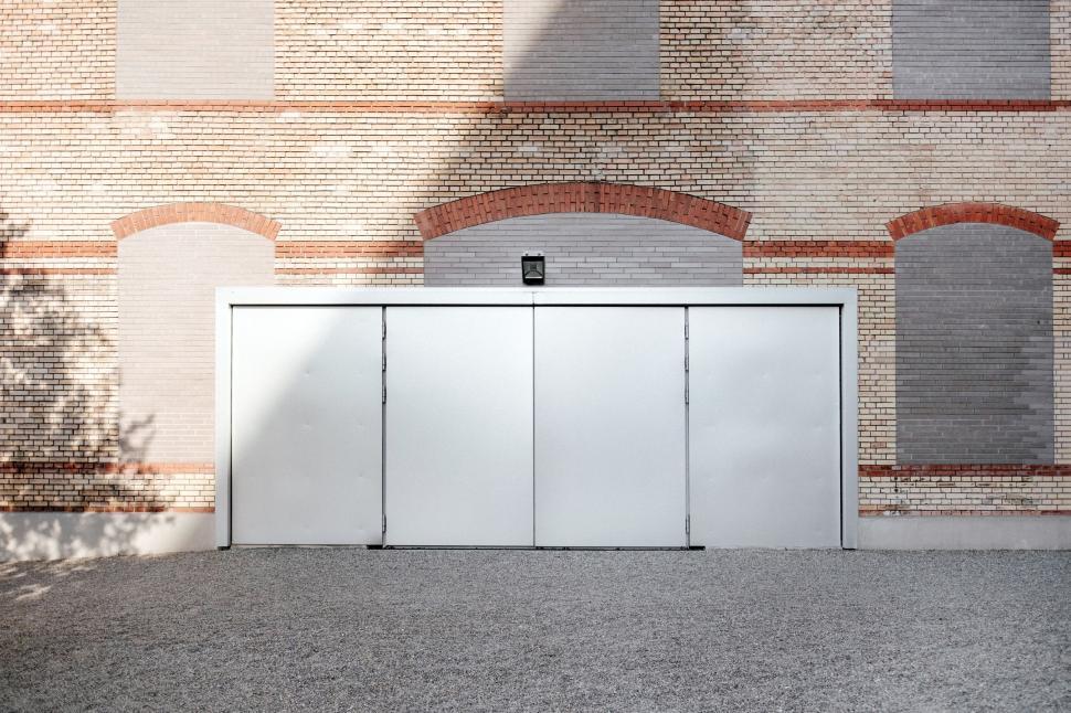 Free Image of White Garage Door in Front of Brick Building 