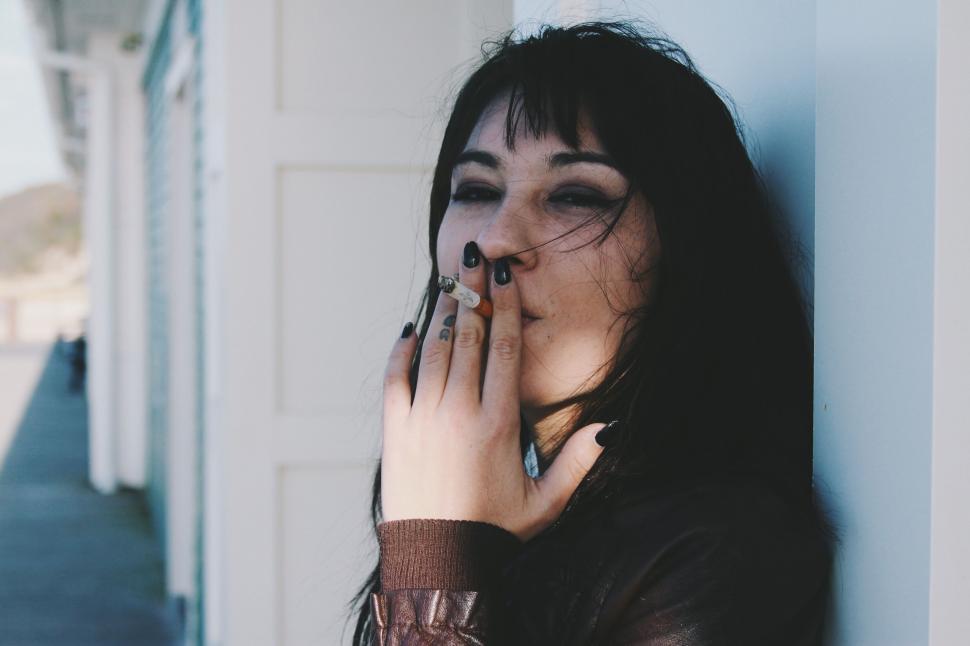 Free Image of Woman With Black Hair and Piercings Holding Hand Up to Face 