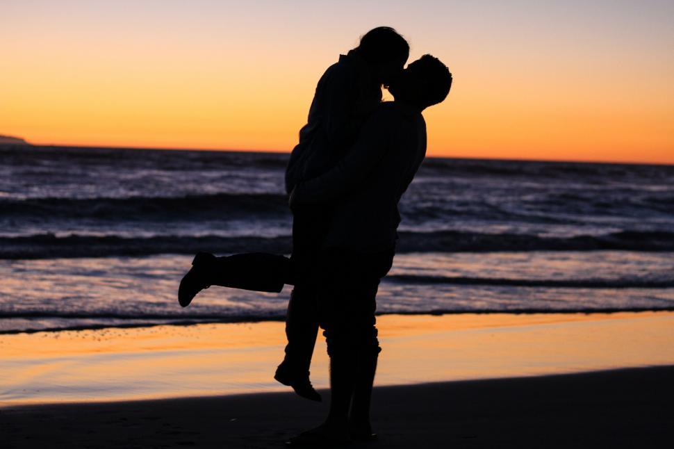 Free Image of Man and Woman Kissing on Beach at Sunset 