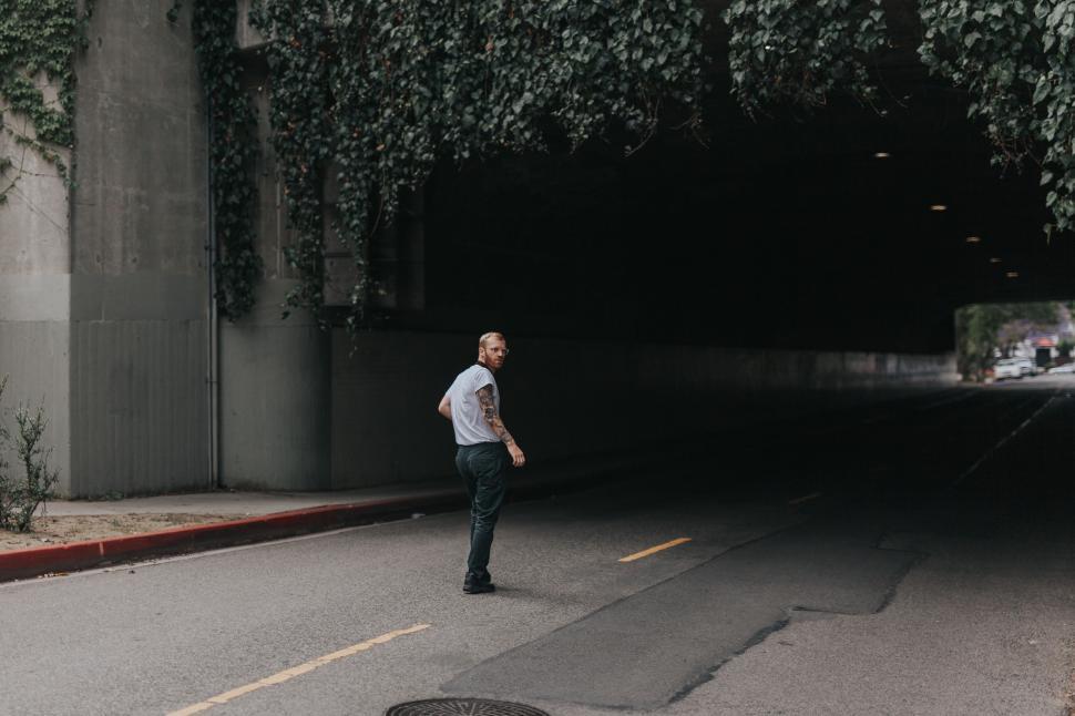 Free Image of Man Standing by Road in Front of Tunnel 