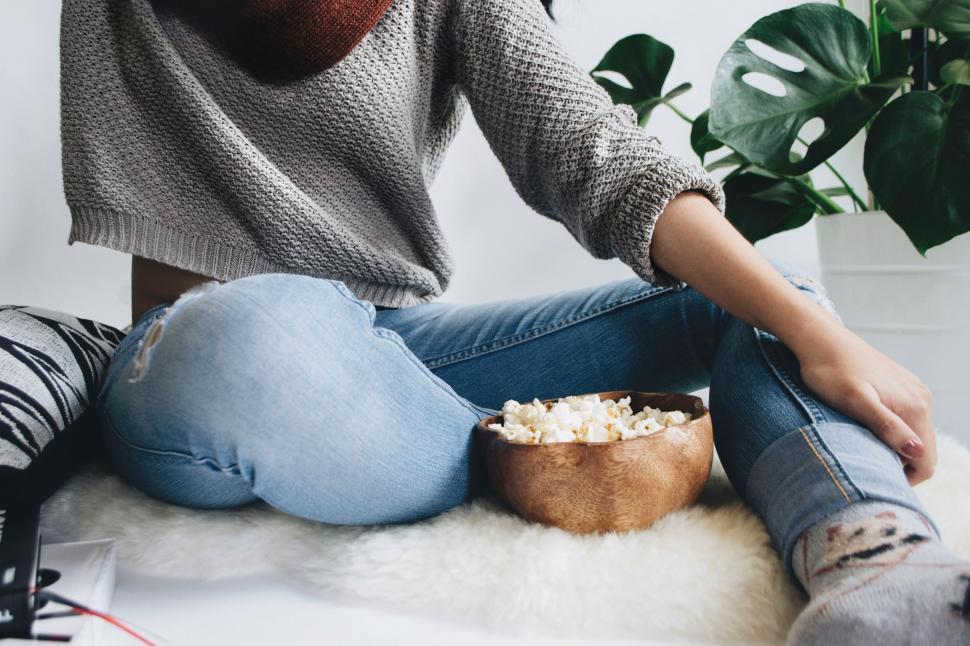 Free Image of Person Sitting on Bed With Bowl of Popcorn 