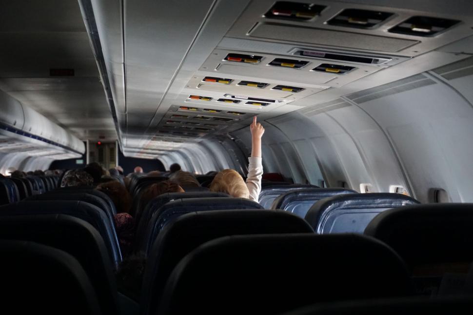 Free Image of Person Reaching Up to Ceiling of Airplane 