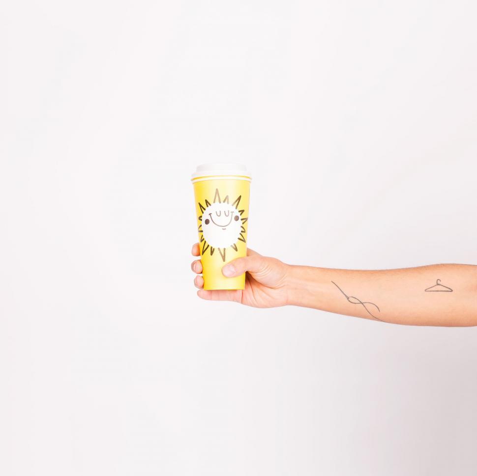 Free Image of Person Holding Yellow Cup With Sun Design 