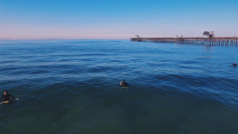 Free Image of Two People Swimming Near Pier 