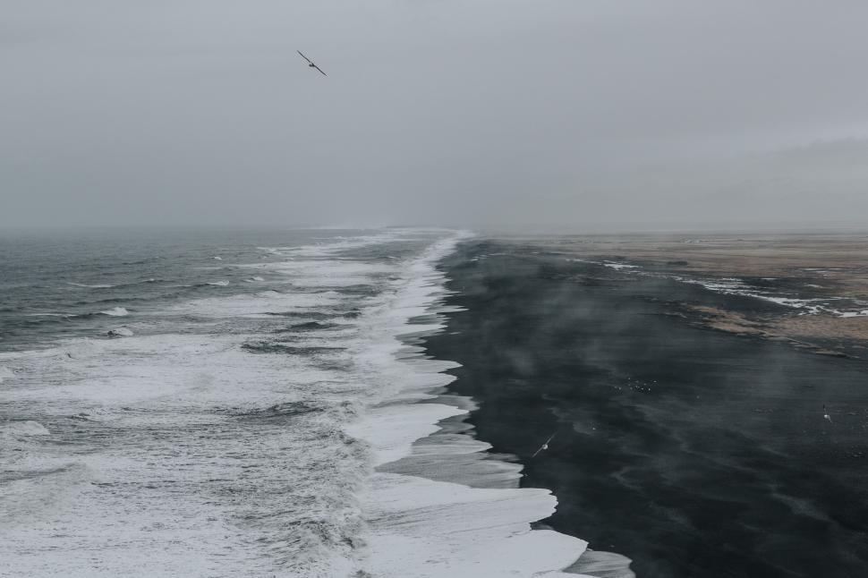 Free Image of Waves Crashing on Rocky Shore Under Overcast Sky 