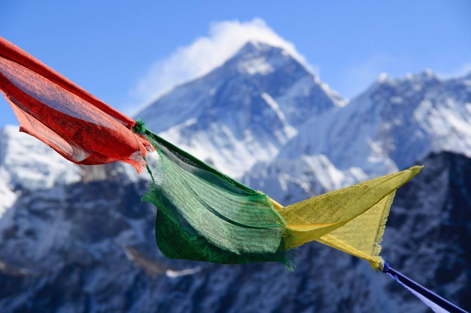 Free Image of Multicolored Flag Flying in Front of Mountain Range 