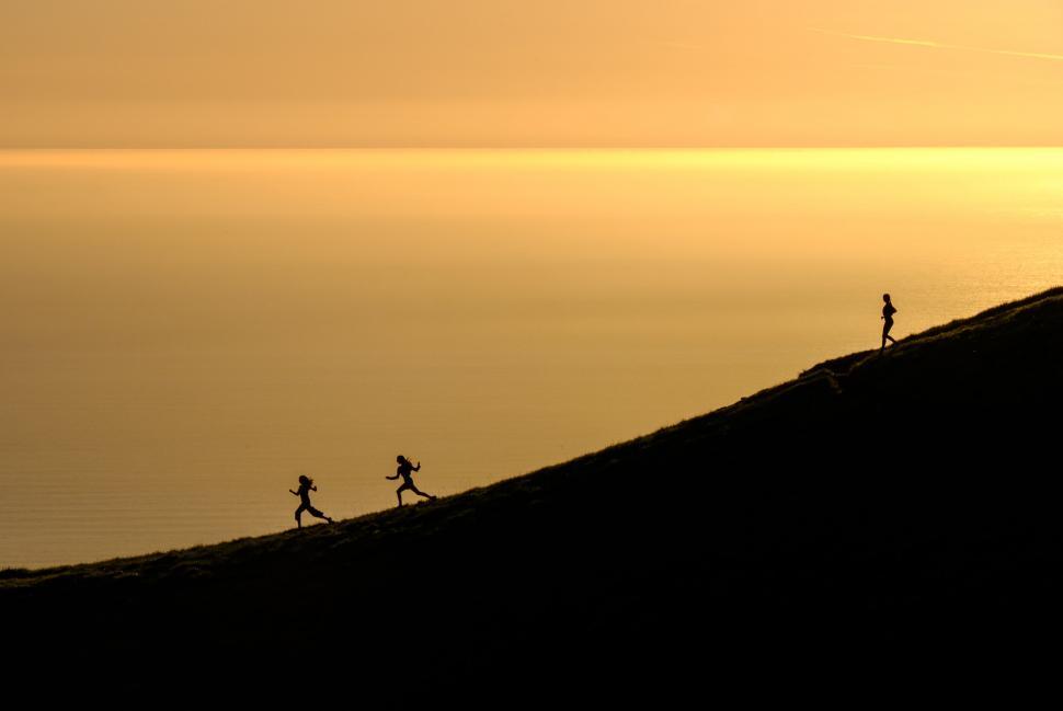 Free Image of Group of People Running Up the Side of a Hill 