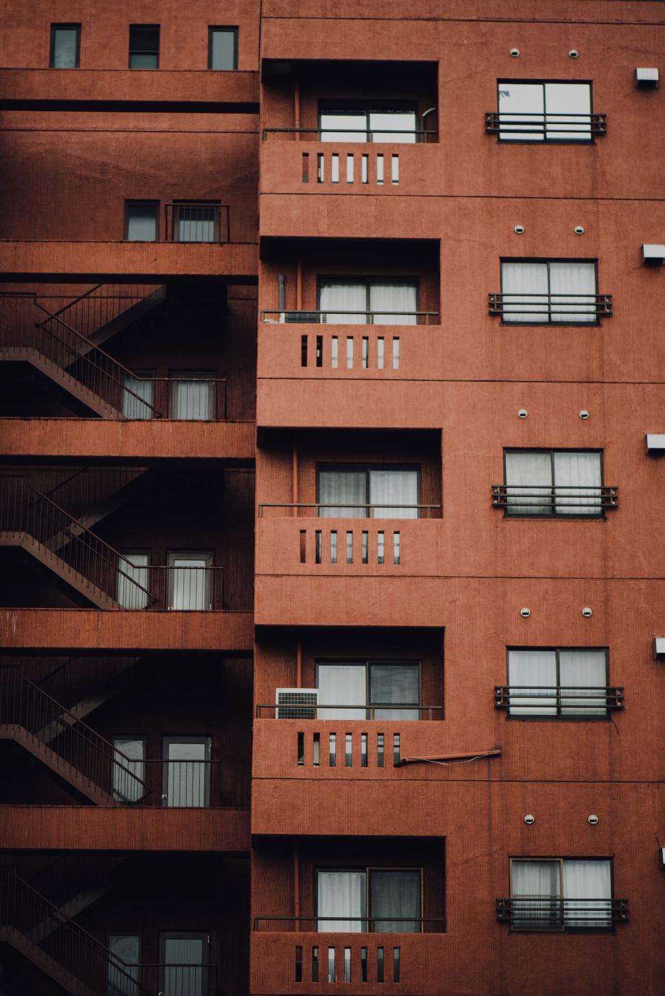 Free Image of Tall Red Building With Balconies and Windows 