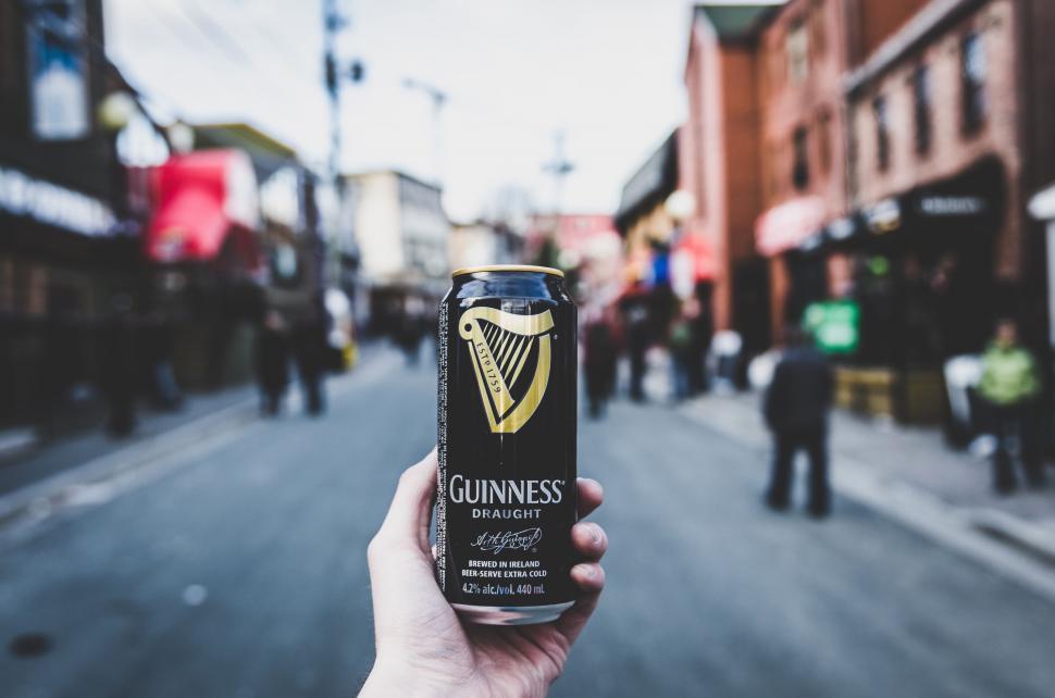 Free Image of Person Holding Can of Guinness on City Street 
