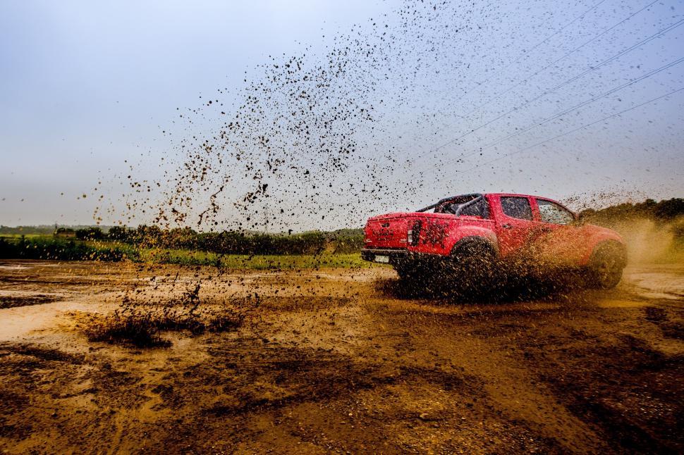 Free Image of Red Truck Driving Through Dirt Field 