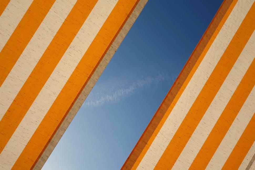 Free Image of Orange and White Striped Wall Against Blue Sky 