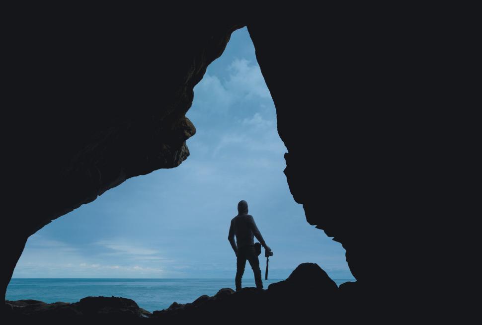 Free Image of Man Standing Inside Cave Next to Ocean 